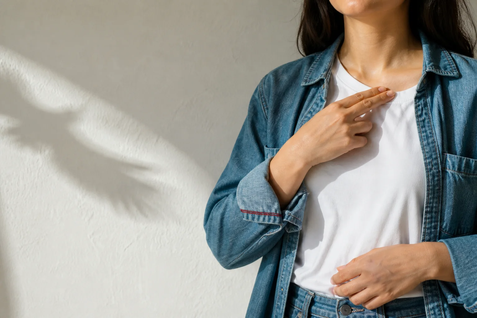 A young adult demonstrates gentle EFT tapping below the collarbone